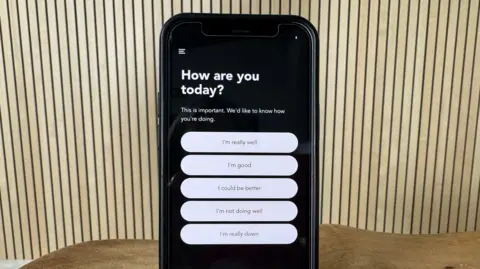 A mobile phone displays the question "How are you today?" with five possible answers for a patient to choose from - ranging from "I'm really well" to "I'm really down".