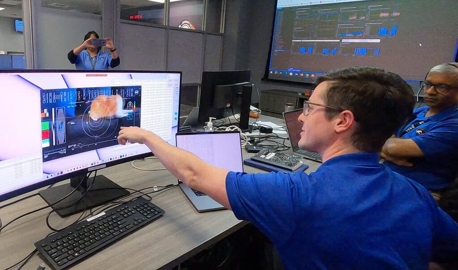 A man sitting at a desk points to a computer monitor that shows a test video of a cat.