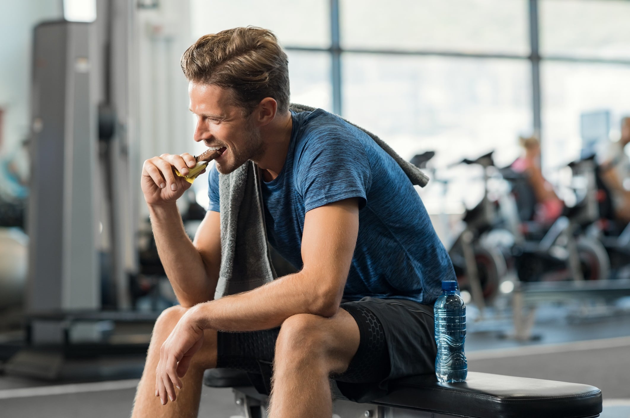 Man eating energy bar at gym.