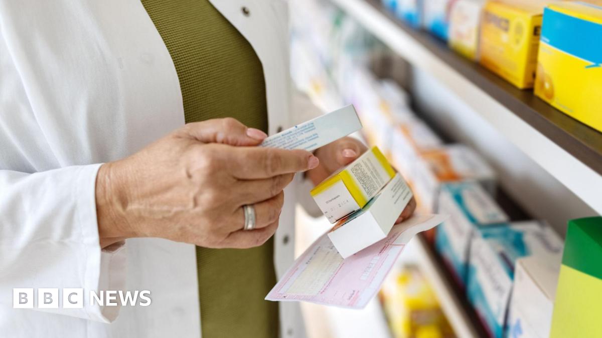 Close up of female pharmacist looking for medicines by the rack. Chemist searches the medicines on storage shelf, focus on hands holding medicine box.