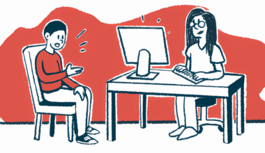 A patient sits with a doctor who is working at a computer.