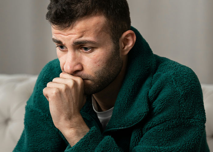 Worried man in green jacket sitting indoors, reflecting on delayed help and facing shocking medical consequences.