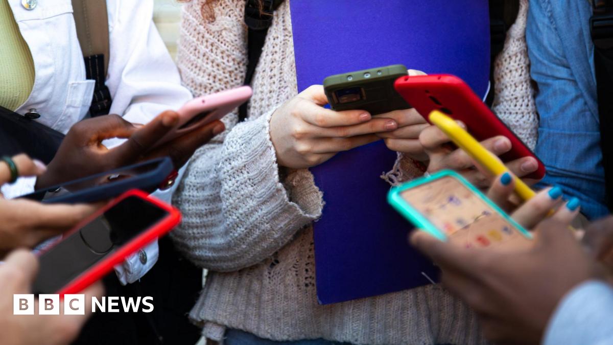 A group of children in school holding phones.