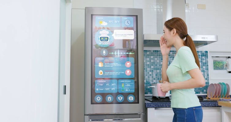 Woman with a ponytail looking at a refrigerator door that shows icons and widgets