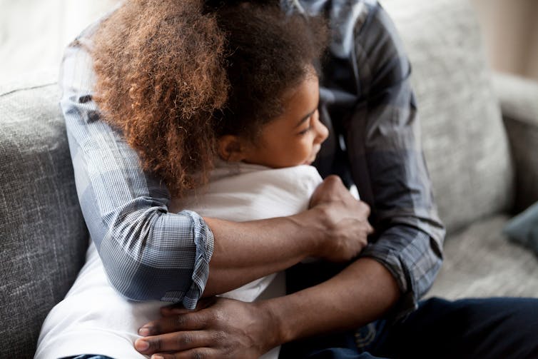 A black man embracing his daughter.
