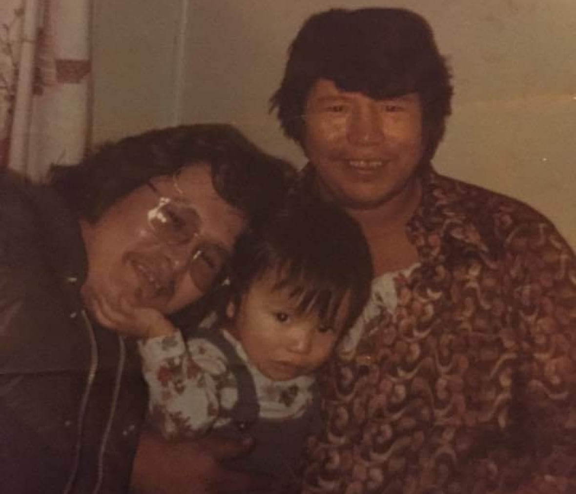 A dated family photo shows two men cuddling a toddler.