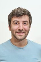 headshot of man wearing a blue t-shirt.
