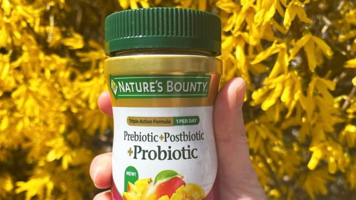 A hand holding a bottle of Nature's Bounty supplements