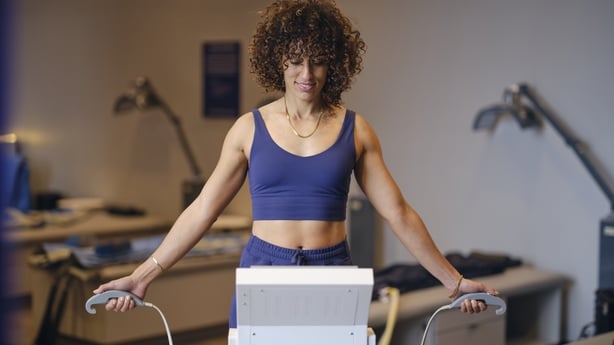 A woman in a biohacking facility, using a body composition analysis machine.