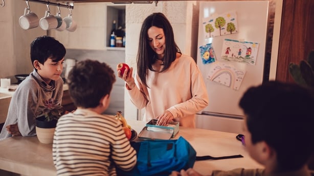 Mother preparing lunch boxes with healthy food and snacks for sons before going to school