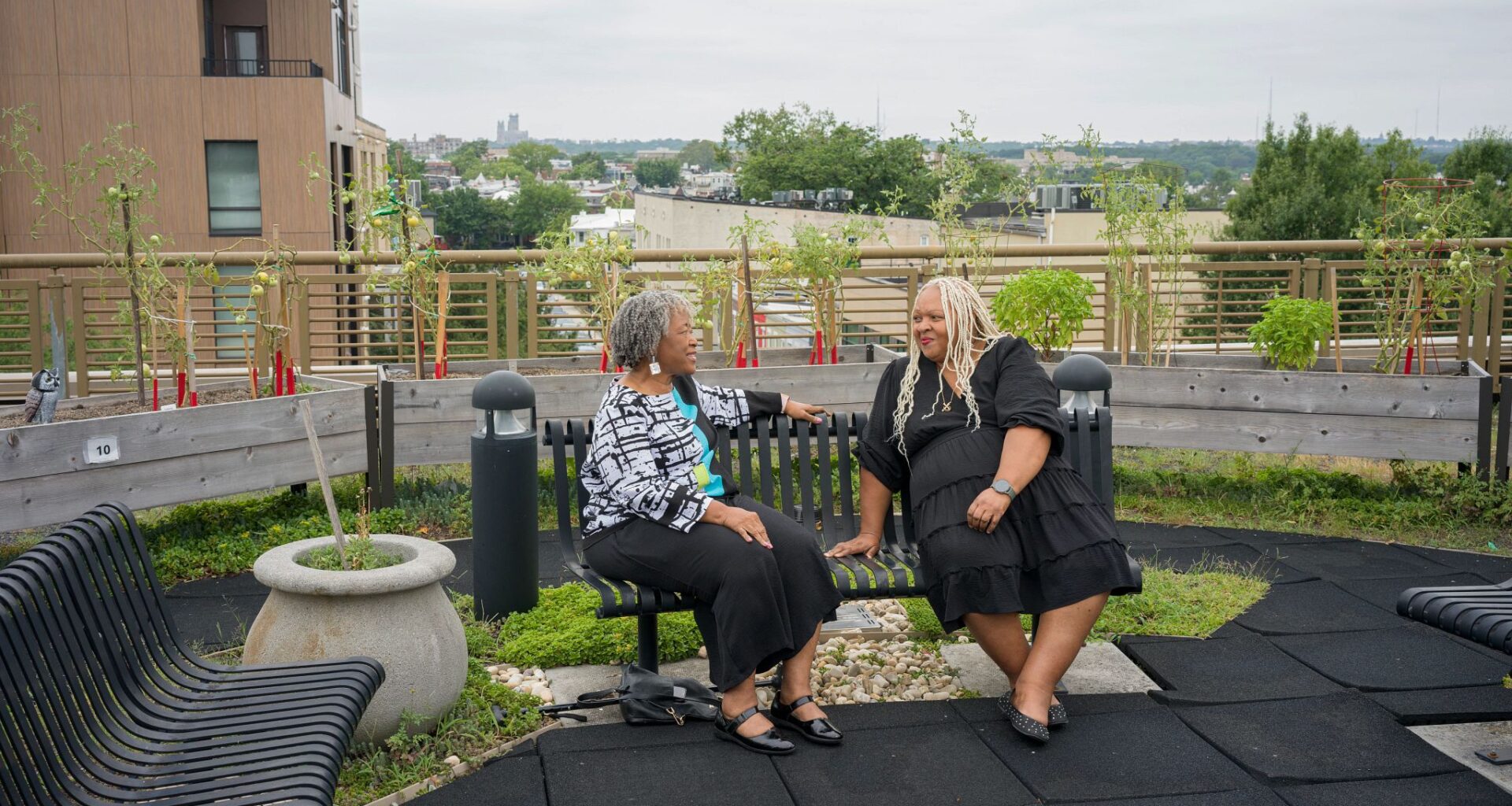 A photo shows grandparent Angela Jasper (on the left) offering a sympathetic ear (with no judgment) to visitor Robin Baxter on a Friendship Bench on the roof of the Bernice Fonteneau Senior Wellness Center in Washington, D.C.