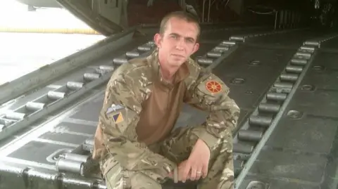 PA Media Cameron Alexander in his Army uniform sitting on a large metal door of an aircraft.