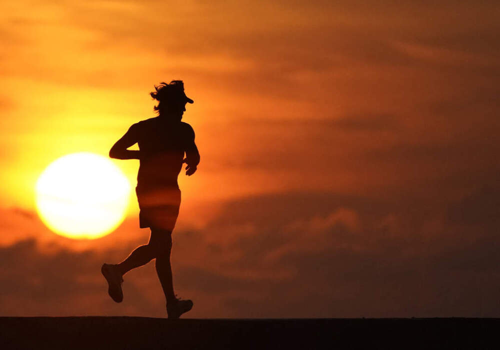 FILE - A jogger is silhouetted while running on a jetty at sunrise over the Atlantic Ocean in Bal Harbour, Fla., on Sept. 19, 2020. (AP Photo/Wilfredo Lee, File)