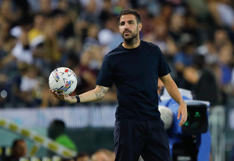 Como coach Cesc Fabregas holds the ball, ready to throw it back into play