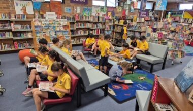 A dozen students sit in a library quietly reading