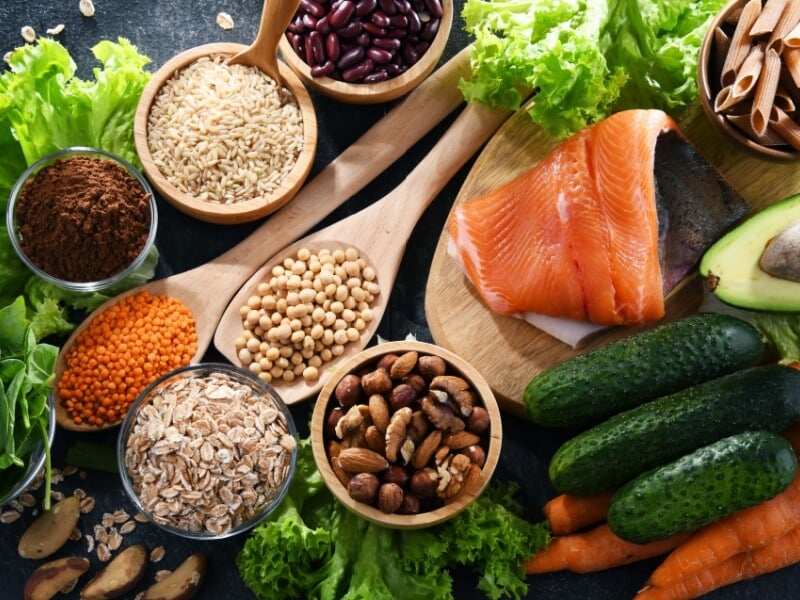 A table with healthy foods like salmon, wholegrains, vegetables, nuts and beans.