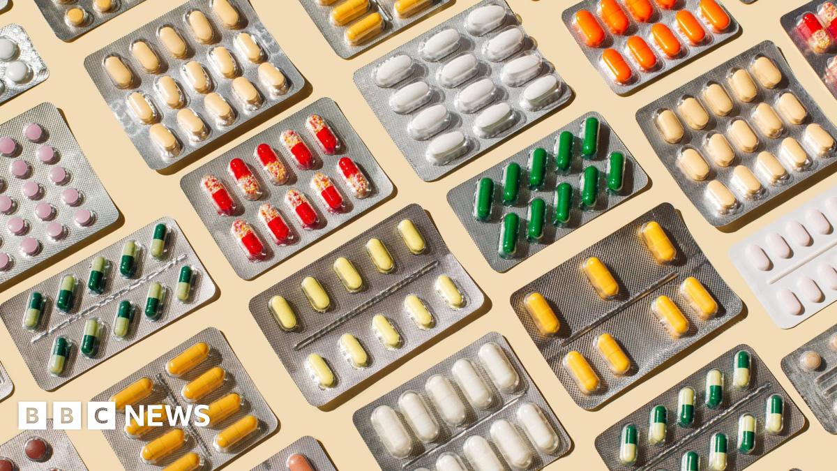A stock image of many medications laid out in blister packs on a pale-coloured table.