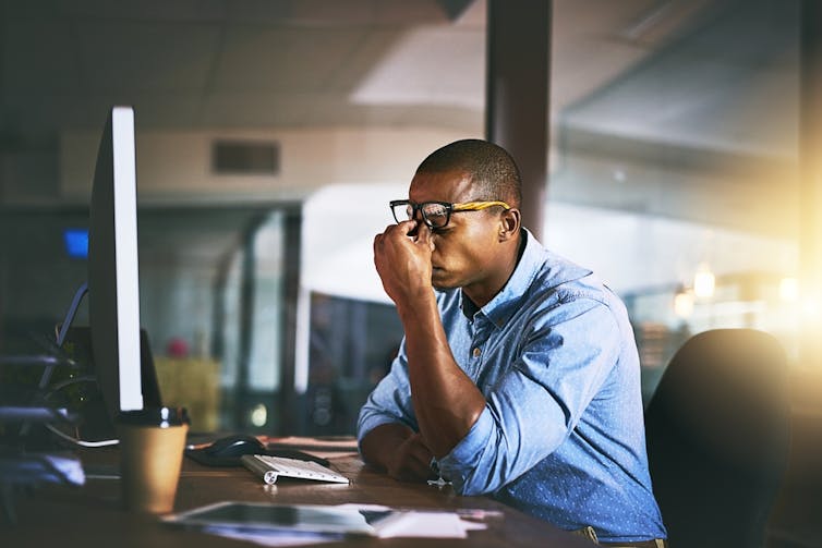 A stressed man at work in front of his computer.