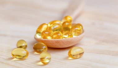 Vitamin E supplements on a wooden spoon, some have spilled onto the table.