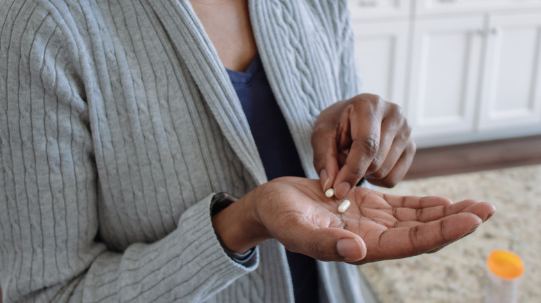 A hand holding medication capsules