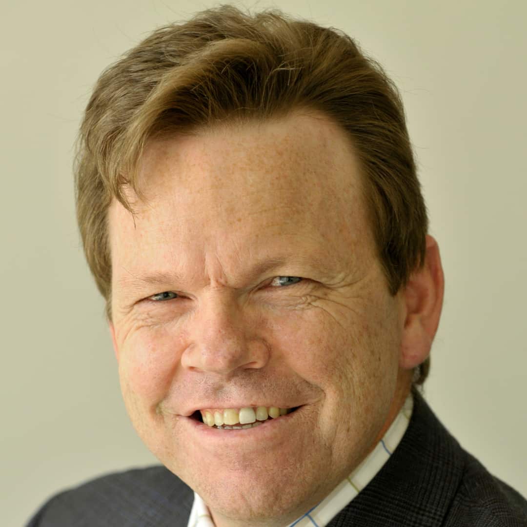 A man in a suit with brown hair smiling
