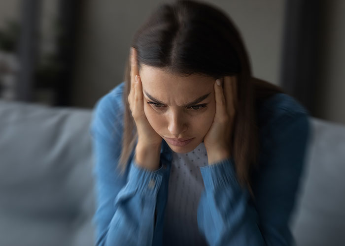 Young woman holding her head in pain, illustrating the impact of doctors getting diagnoses wrong on patients.