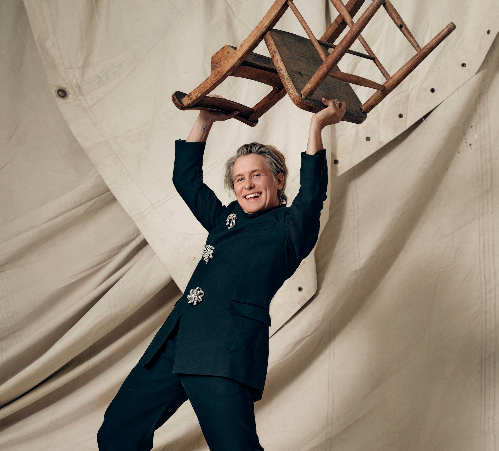Gary Barlow of Take That lifting a chair above his head.