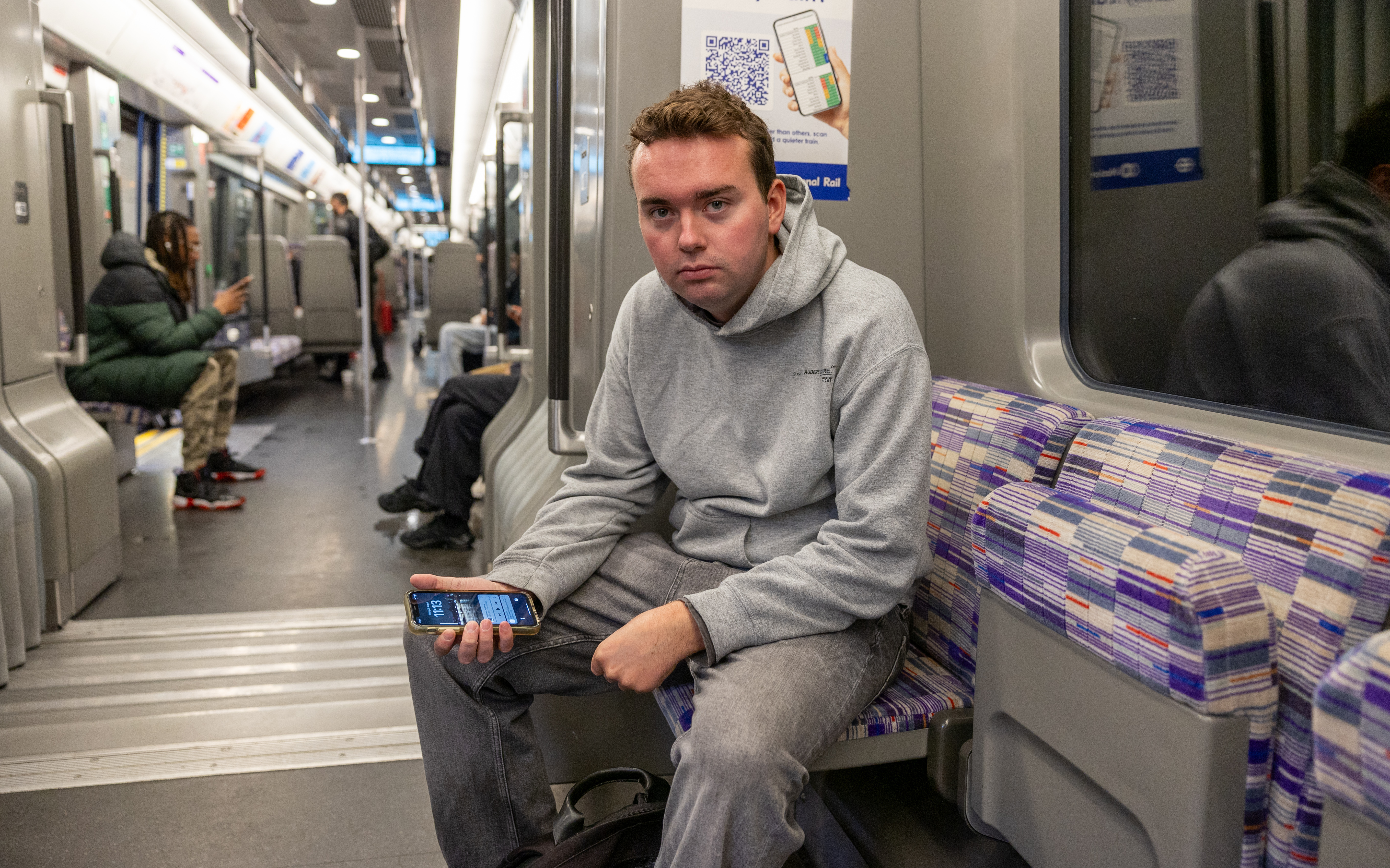 Man sitting on a London train, looking at his phone.