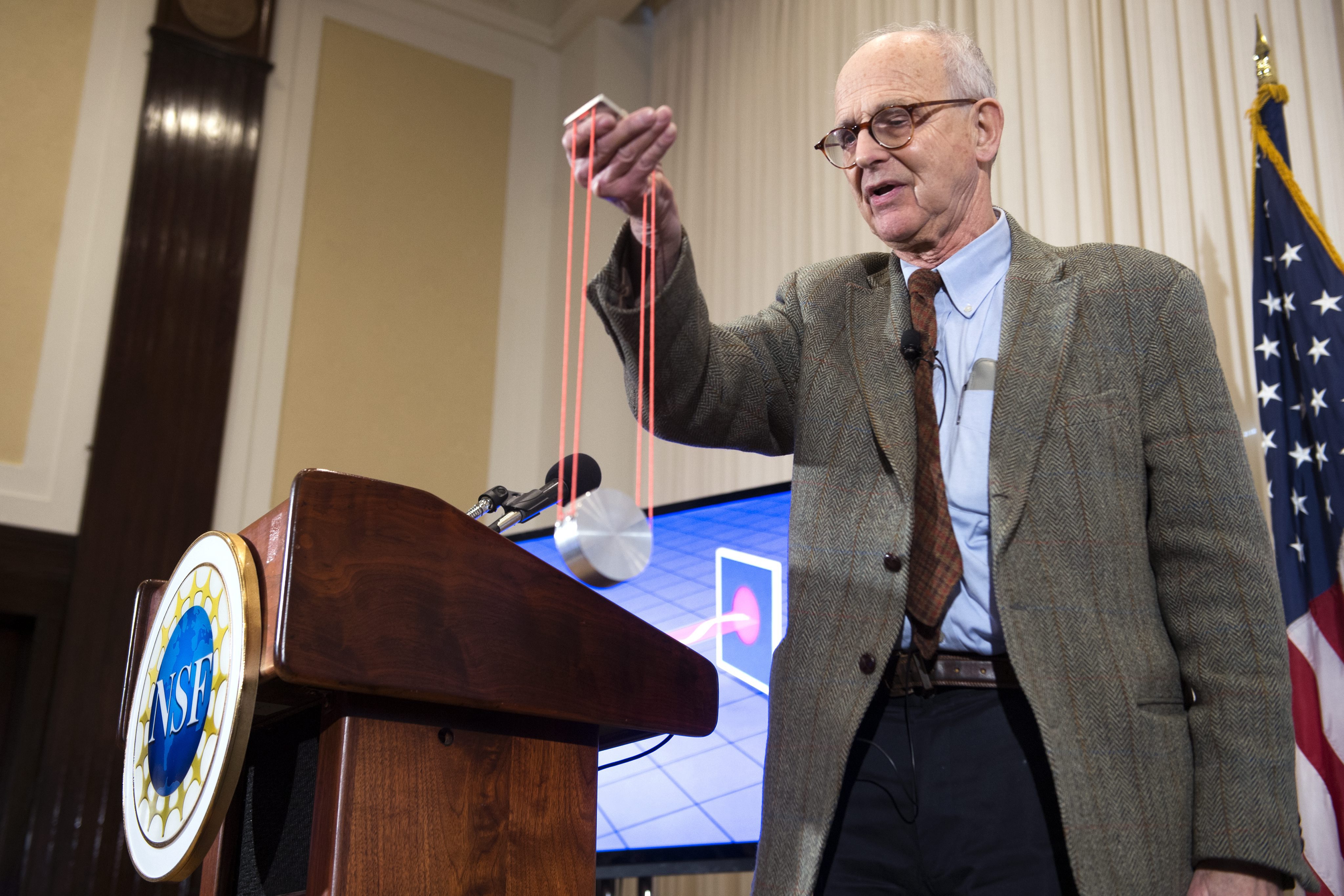 Professor Rainer Weiss demonstrating gravitational waves at a press conference.