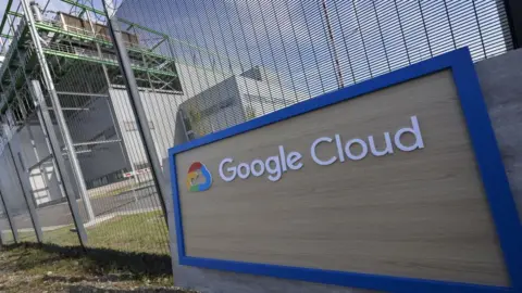 Bloomberg via Getty Images A Google Cloud sign sits in front of a wire fence. Behind is a data centre.