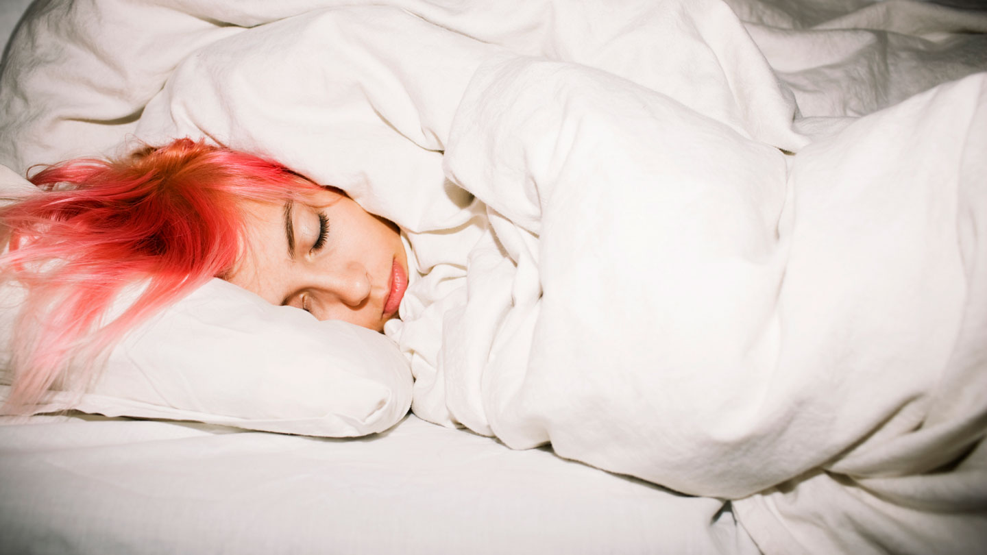 a pink haired teen's head is sleeping in a bundle of white sheets and blankets
