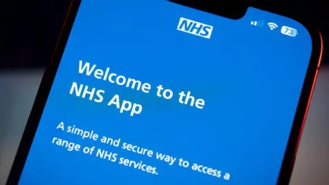 Getty Images Close-up phone screen, with Welcome to the NHS App message visible in white on a blue background.  