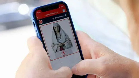 ADNAN BECI/AFP A woman holds a mobile phone with the AI image of a woman dressed in a white veil