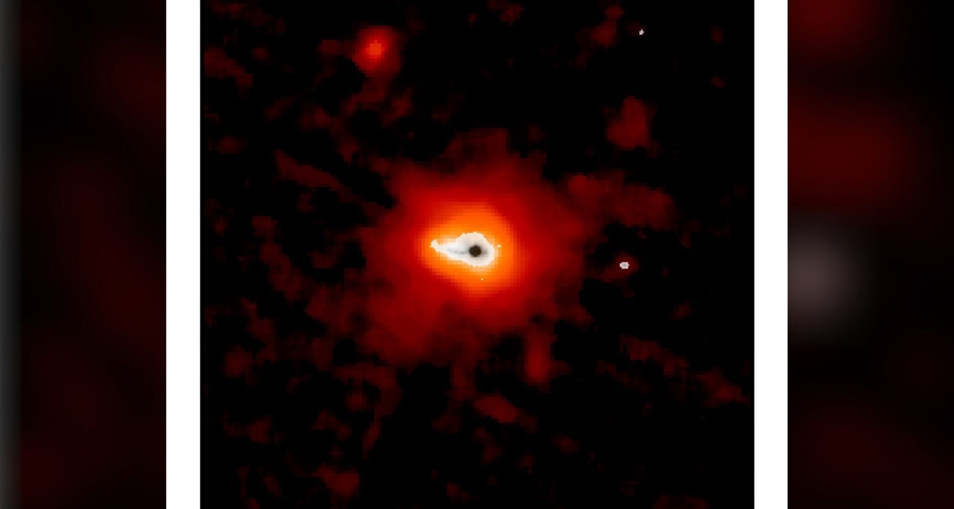 A glowing dark dot surrounding by blobs of white, orange and red light sits on a dark background