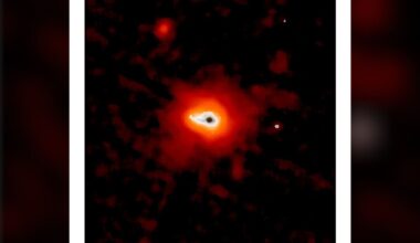 A glowing dark dot surrounding by blobs of white, orange and red light sits on a dark background