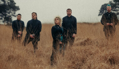 Forlorn stood in a field of tall grass - their singer is wearing a flower crown