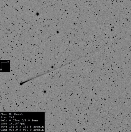 Sky photo with stars in black on white showing a small black object with a very long tail.