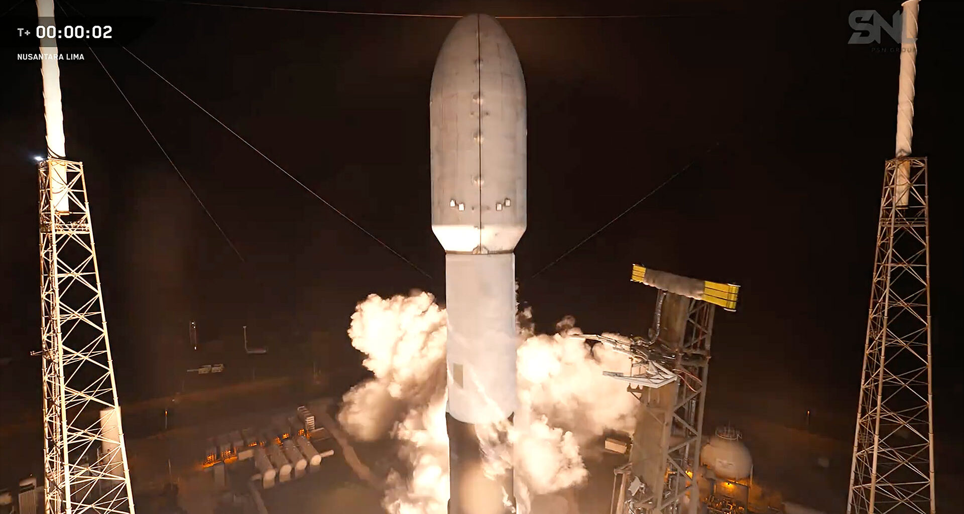 a camera mounted on a nearby tower captures the head-on view of a rocket as it begins to lift off the launch pad into the night sky.