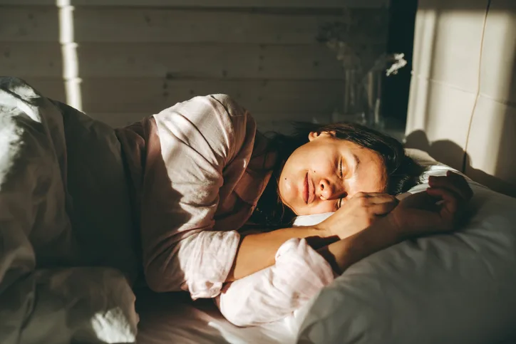 Woman sleeping peacefully in bed in the morning sunlight