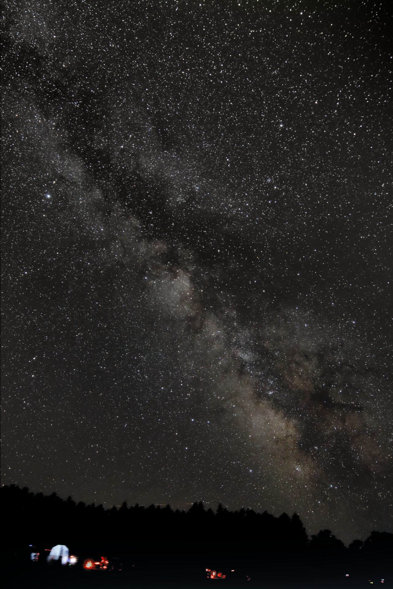 a streak of white cloudy light crosses the night sky