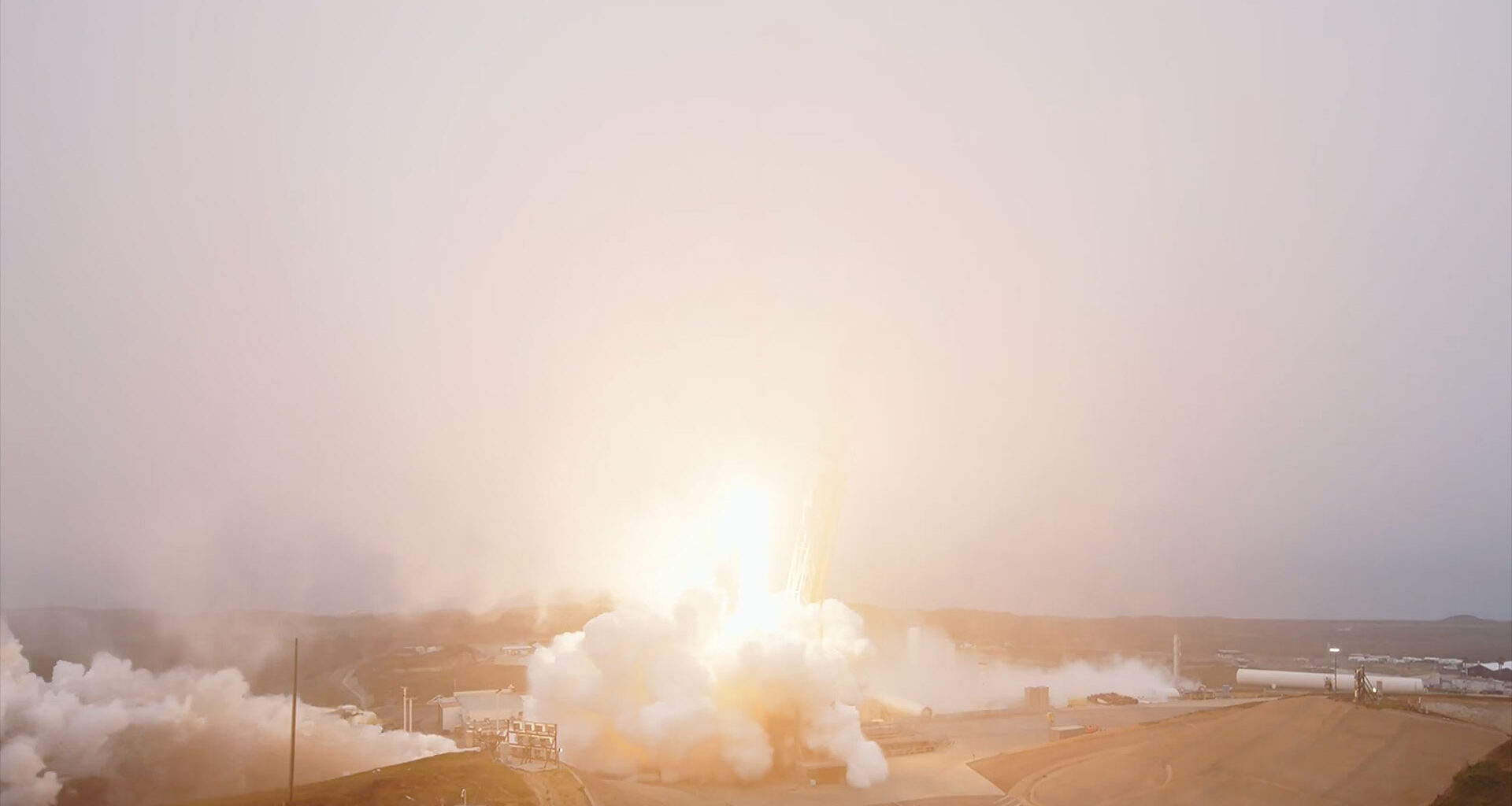 A rocket lifts into a fog layer blanketing its launch site, obscuring the view of the booster.