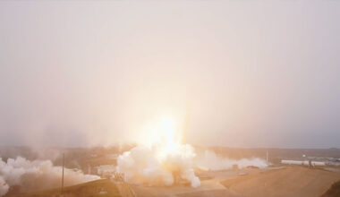 A rocket lifts into a fog layer blanketing its launch site, obscuring the view of the booster.