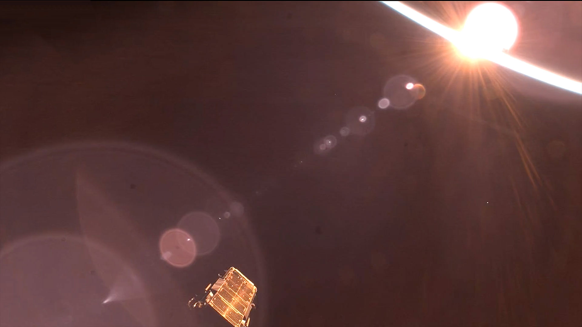 a satellite (lower left of center) is seen after deployment in the light of an orbital sunrise