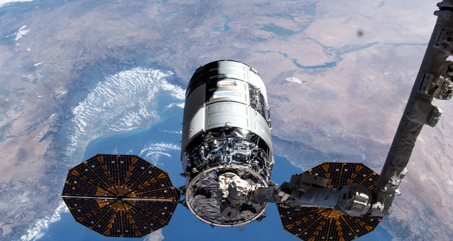 Northrop Grumman&rsquo;s 21st Cygnus cargo craft, with its prominent cymbal-shaped UltraFlex solar arrays, is pictured in the grips of the Canadarm2 robotic arm shortly after its capture on Aug. 6, 2024.