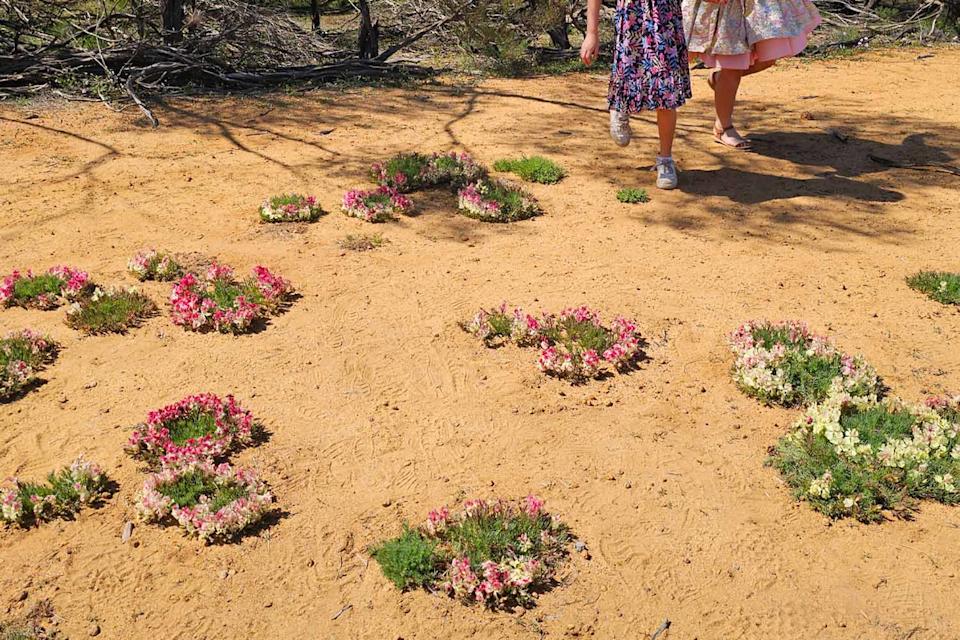 Wreath flowers with two children standing among them.