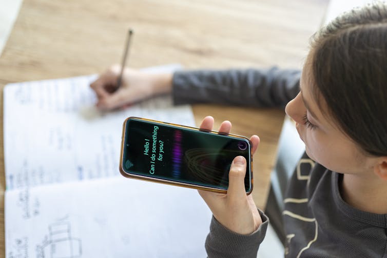Girl doing school with phone and notebook.