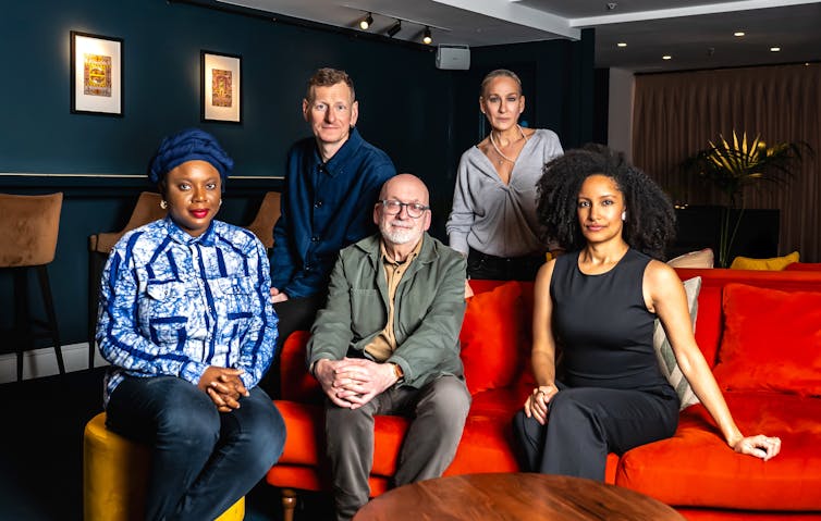 A group of people photographed on a red sofa looking brainy.