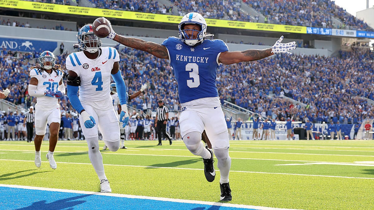 Football player Seth McGowan #3 of the Kentucky Wildcats, in dark blue, runs for a touchdown against the Ole Miss Rebels.