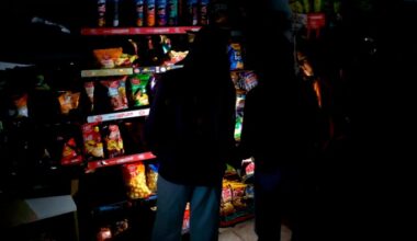 Customers use mobile phone flashlights to browse shelves in a dark supermarket during a power outage in Barcelona, Spain on April 28, 2025.