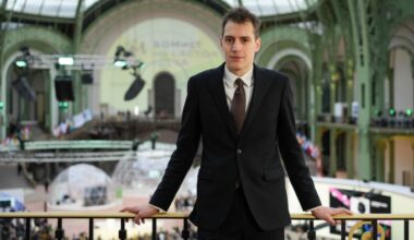 Arthur Mensch, founder of Mistral AI, stands in a suit at the AI Action Summit venue in Paris, looking toward the camera.